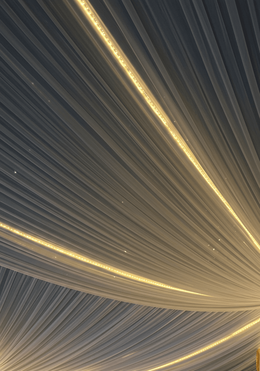 Close-up of white pleated chiffon fabric panels with warm LED strip lighting along edges creating dramatic contrast during evening reception