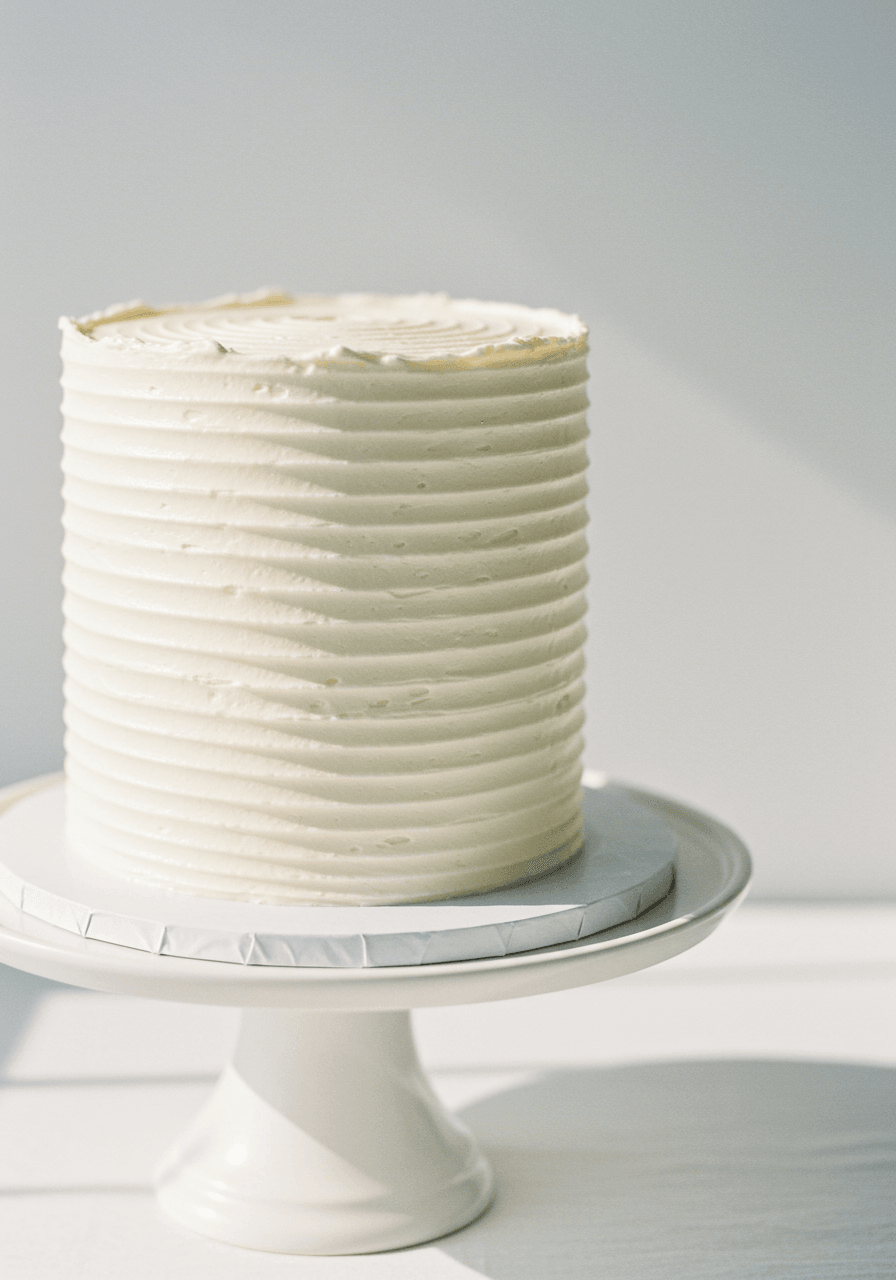 Single-tier wedding cake with delicate vertical ribbed buttercream piping creating silk-like texture with pearl shimmer