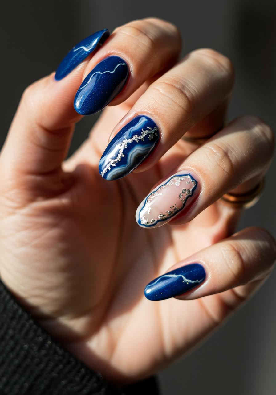 Luxurious sapphire blue geode nail art with crystalline formations and metallic highlights